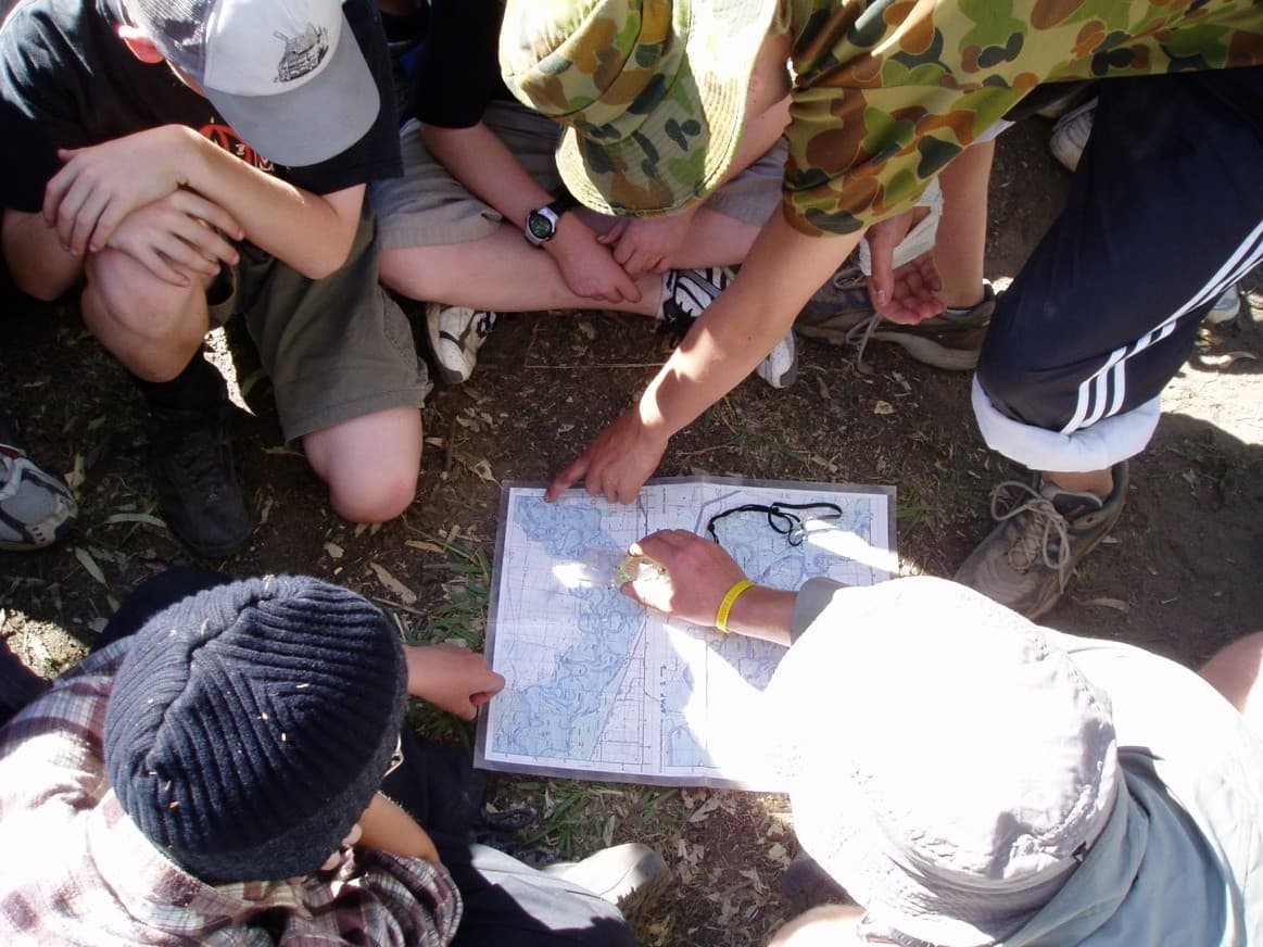 Young people learning navigation skills with a map and compass during an outdoor education program