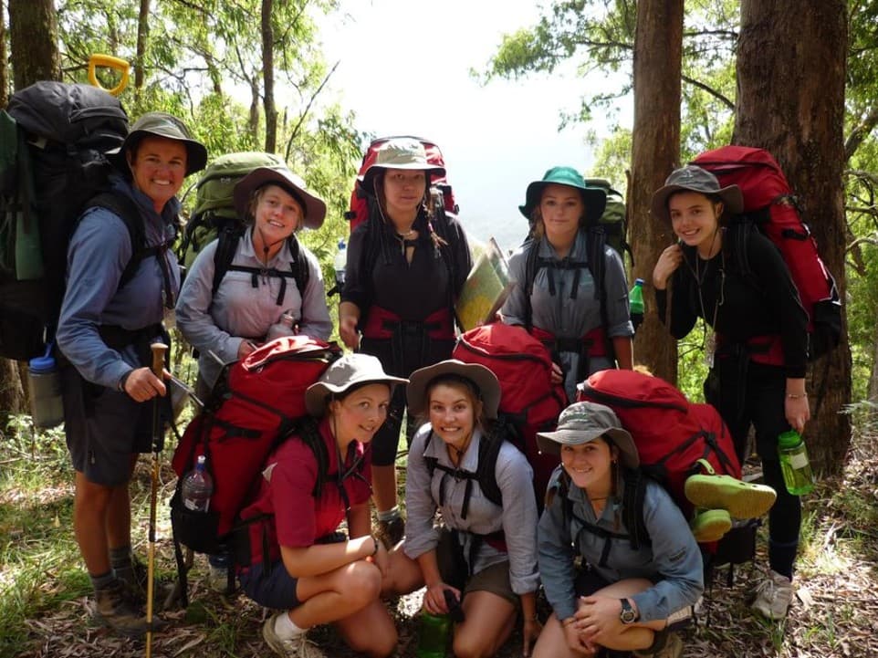 Group of young people with backpacks hiking through the bush on an outdoor education expedition